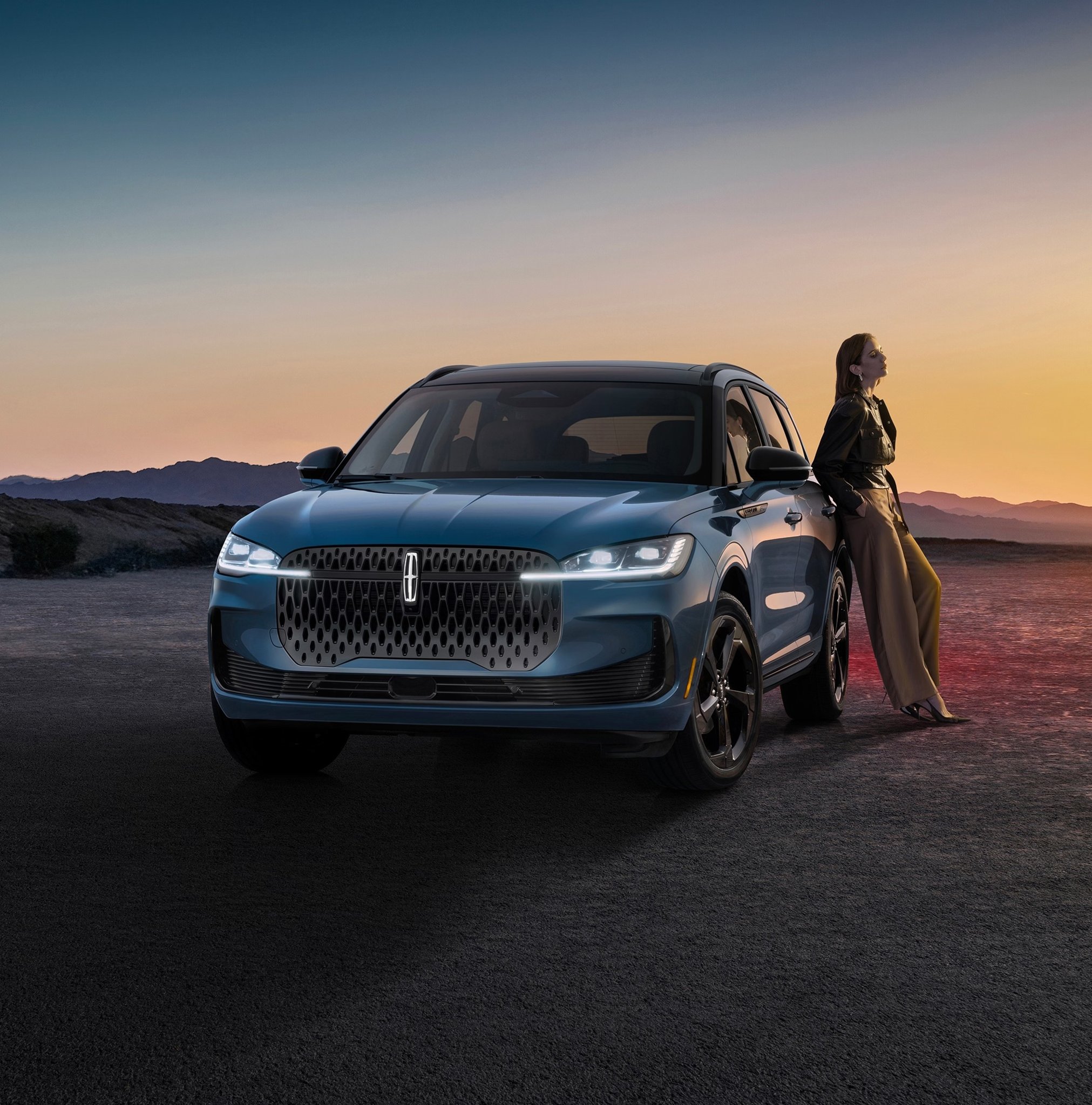 2027 Lincoln Corsair Hybrid front view parked on desert road at dusk with woman